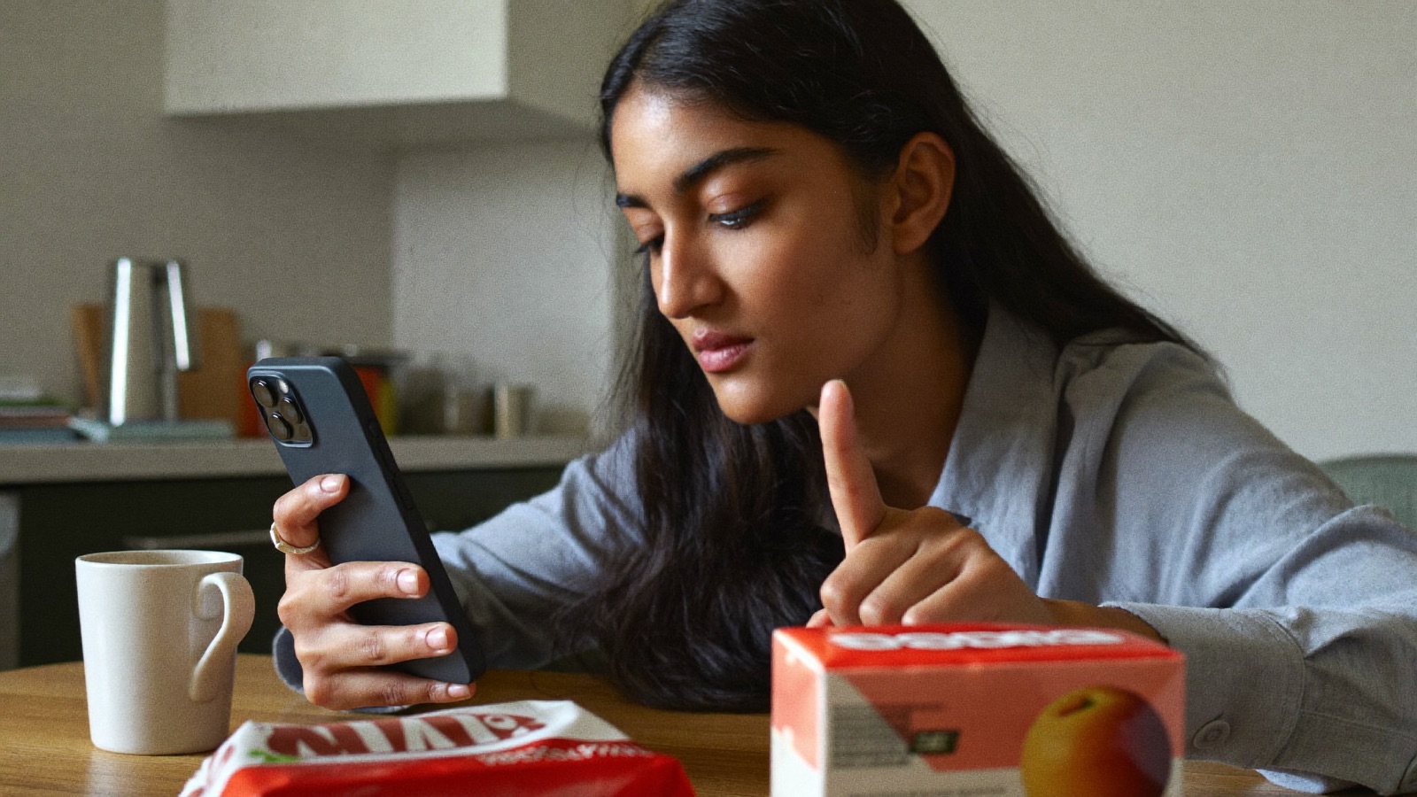 Woman reviewing ingredient scanner app results at home with groceries