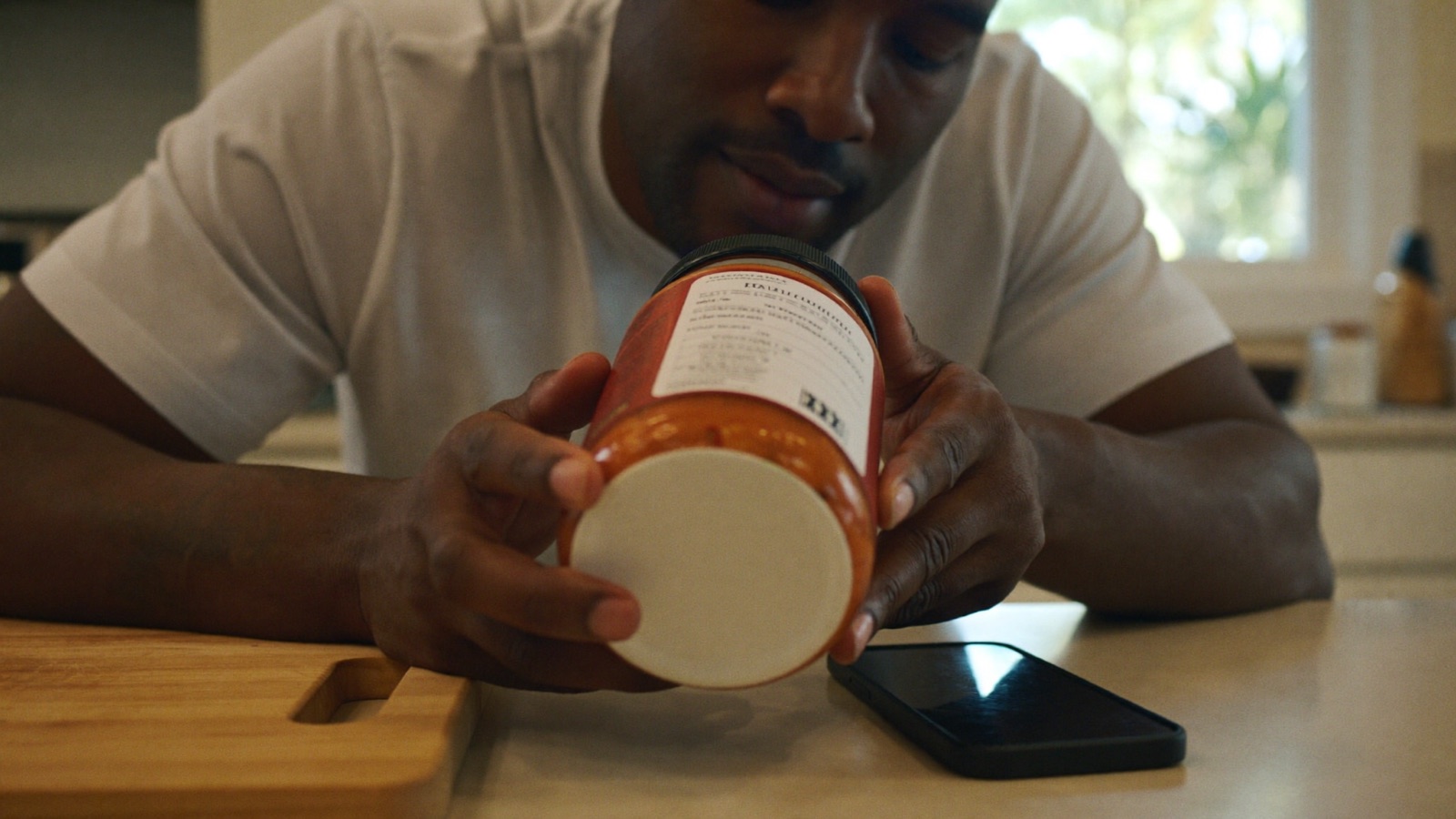 Man cross-checking pasta sauce label against food scanner app data
